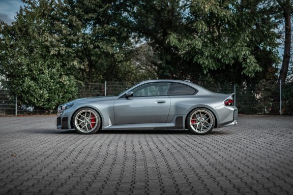 Grauer BMW M2 G87 im Seitenprofil mit tiefergelegtem Fahrwerk und Edelweiss-Rädern in Champagne.