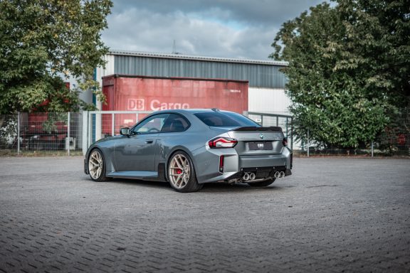 BMW M2 G87 schräg von hinten mit Carbon-Heckspoiler, Diffusor und vier Endrohren der Capristo-Abgasanlage.